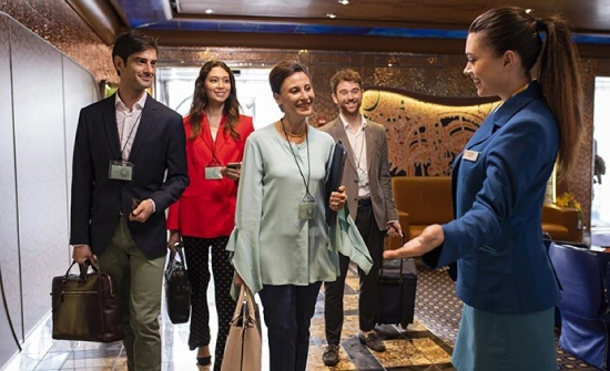 Un groupe de croisiéristes est reçu par une hôtesse d'accueil lors de leur embarquement